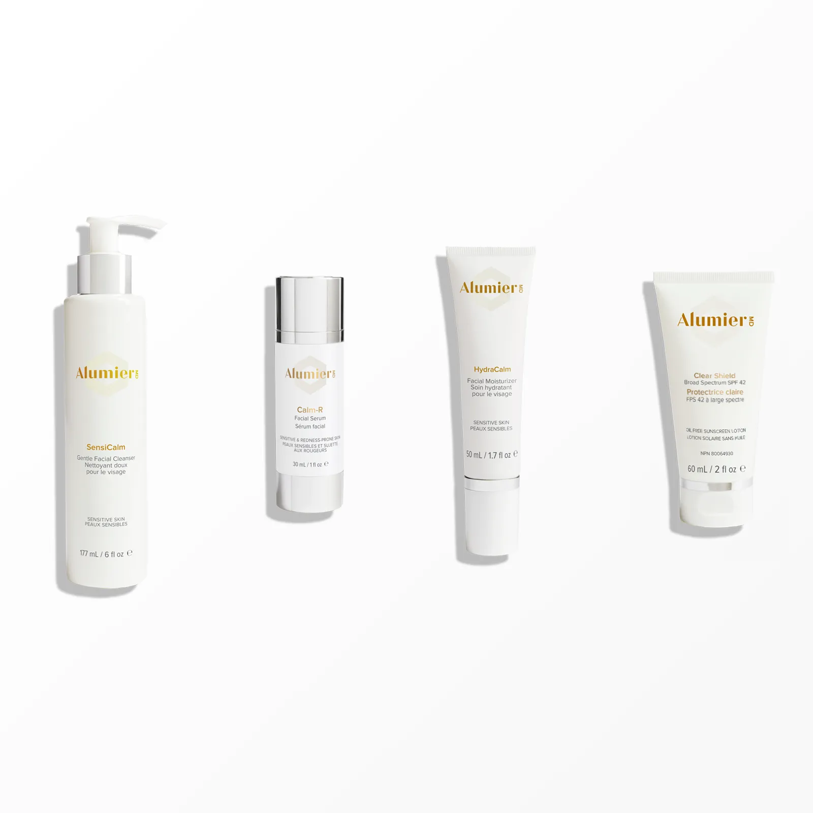 Four bottles of cosmetics are lined up on a white surface.