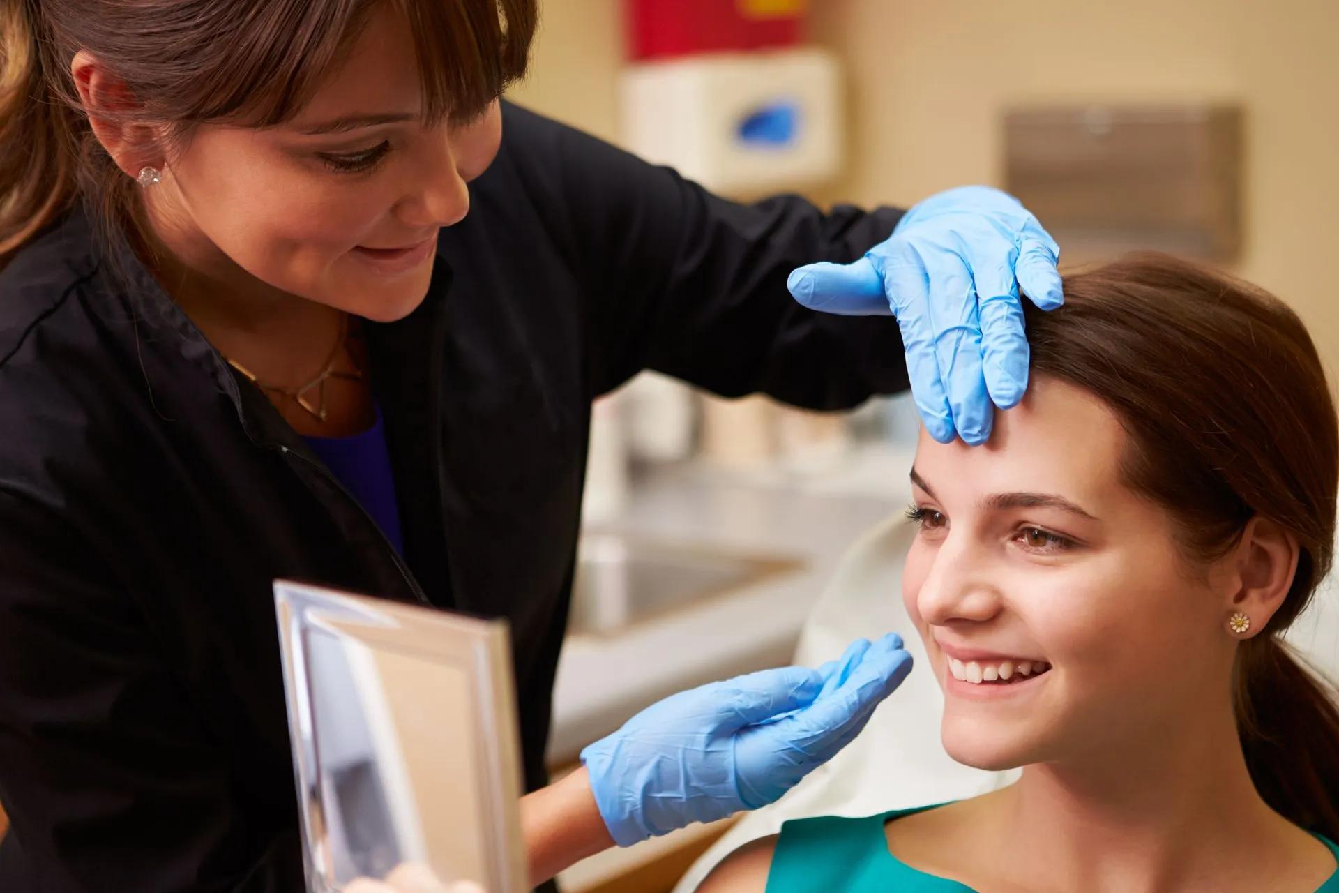 A woman is getting a botox injection on her forehead.