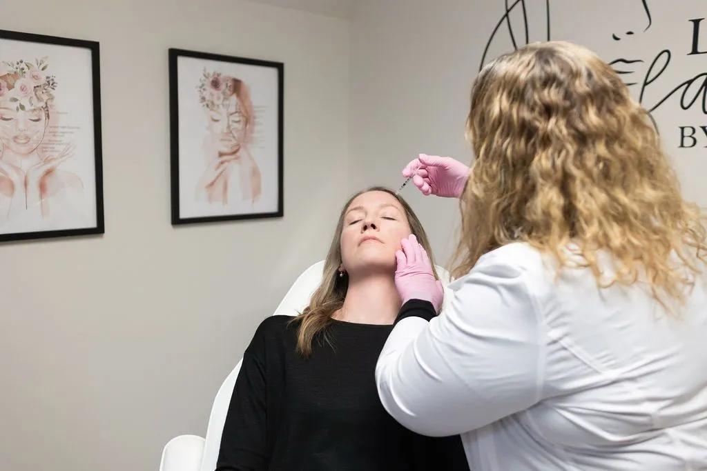 Woman receiving facial injections from a practitioner in a medical setting.